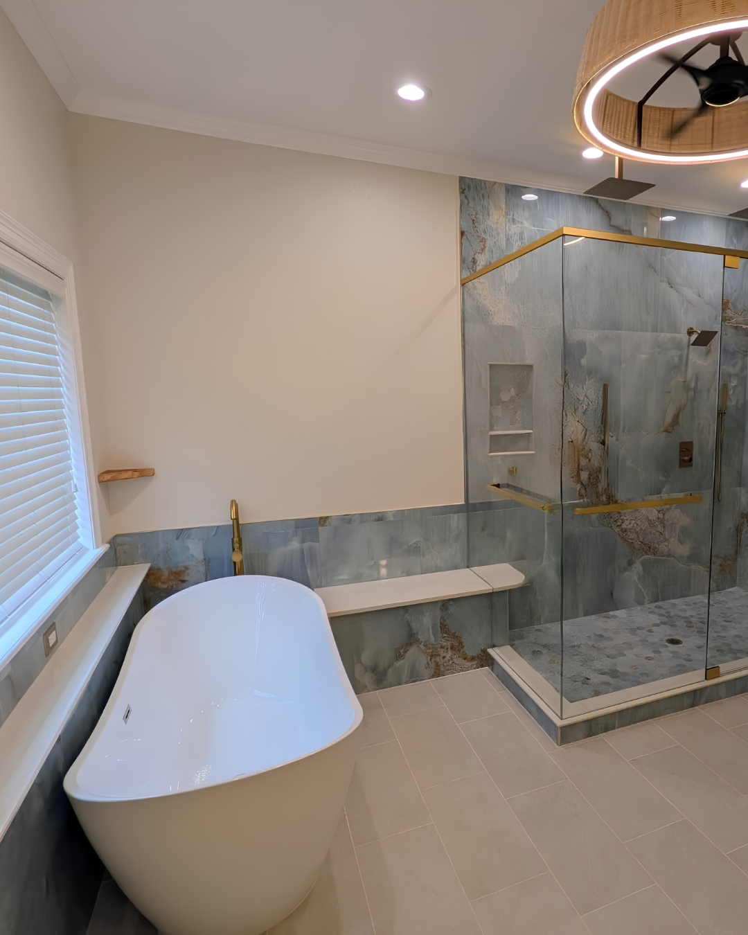 Novara blue stone-look bathroom with frameless shower glass, bench and tub