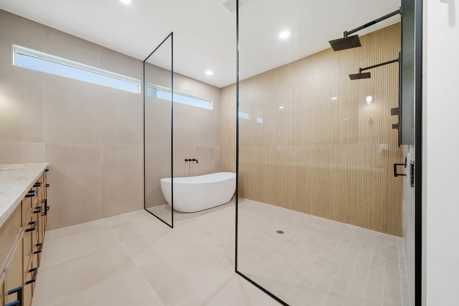 Open wet room with freestanding tub behind glass